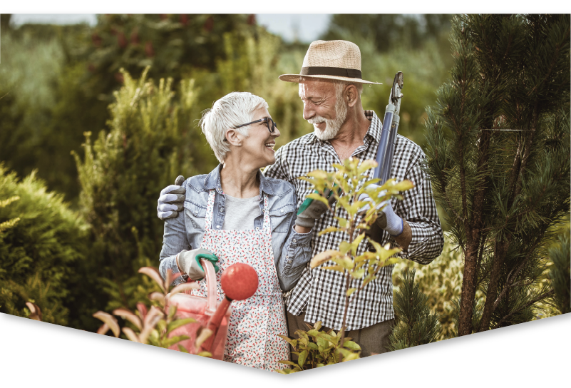 Senior couple look at each other fondly while standing in their garden.